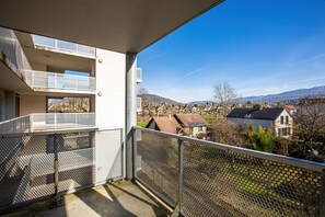 A balcony with a metal railing and a view of a town and mountains in the distance. - ResidHotel Azuréa (Aix-les-Bains)