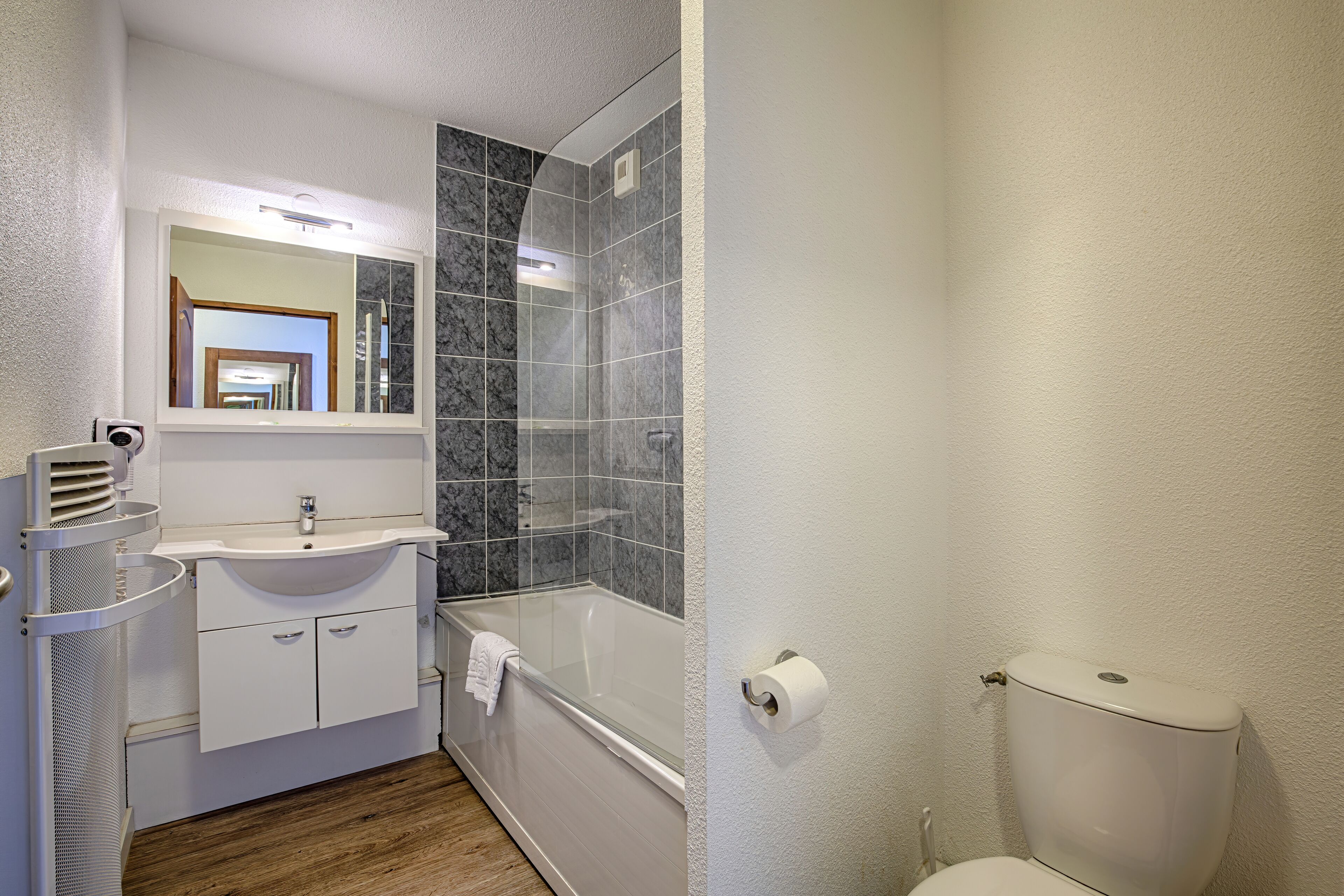 A bathroom with a white sink, mirror, and toilet.