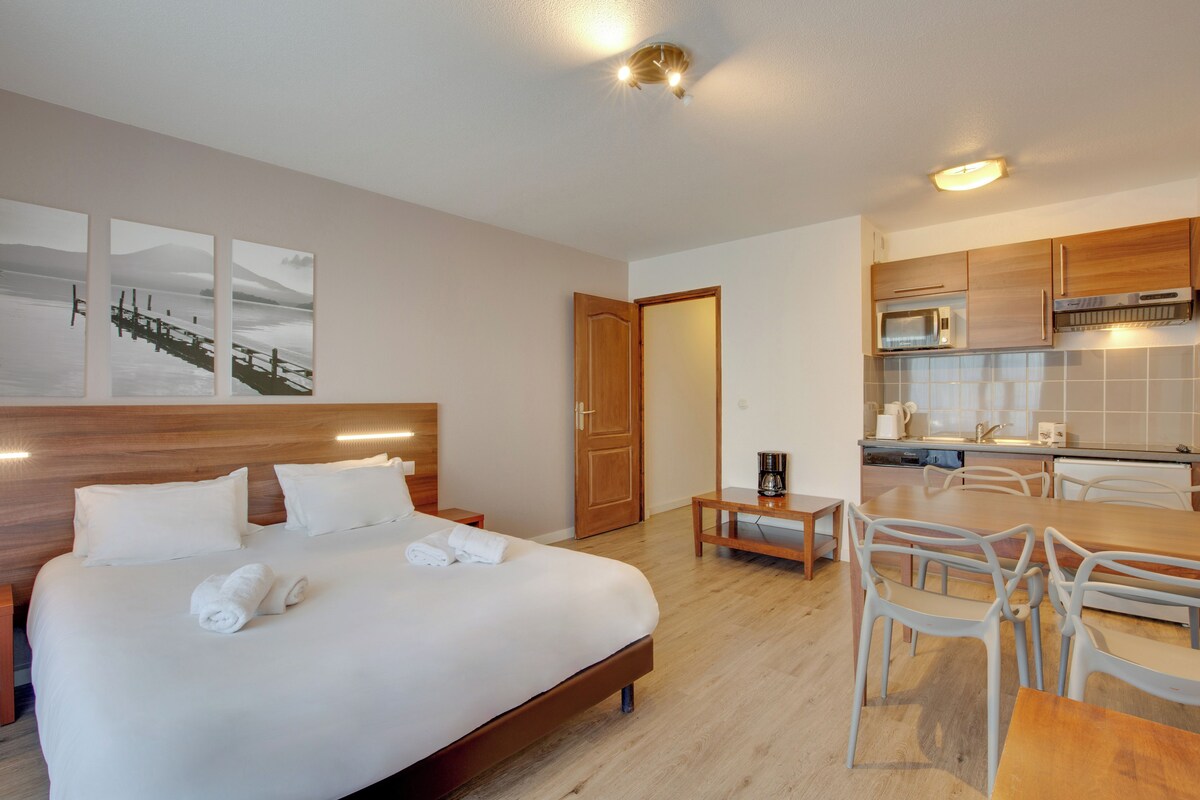 Een hotelkamer met een bed, een tafeltje en een kitchenette.