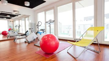 A gym with exercise equipment, a red exercise ball, and a yellow chair.