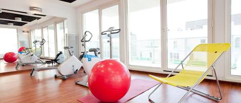 A gym with exercise equipment, a red exercise ball, and a yellow chair.