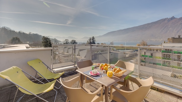 A terrace with a table set for breakfast, overlooking a mountainous landscape. - ResidHotel Azuréa (Aix-les-Bains)