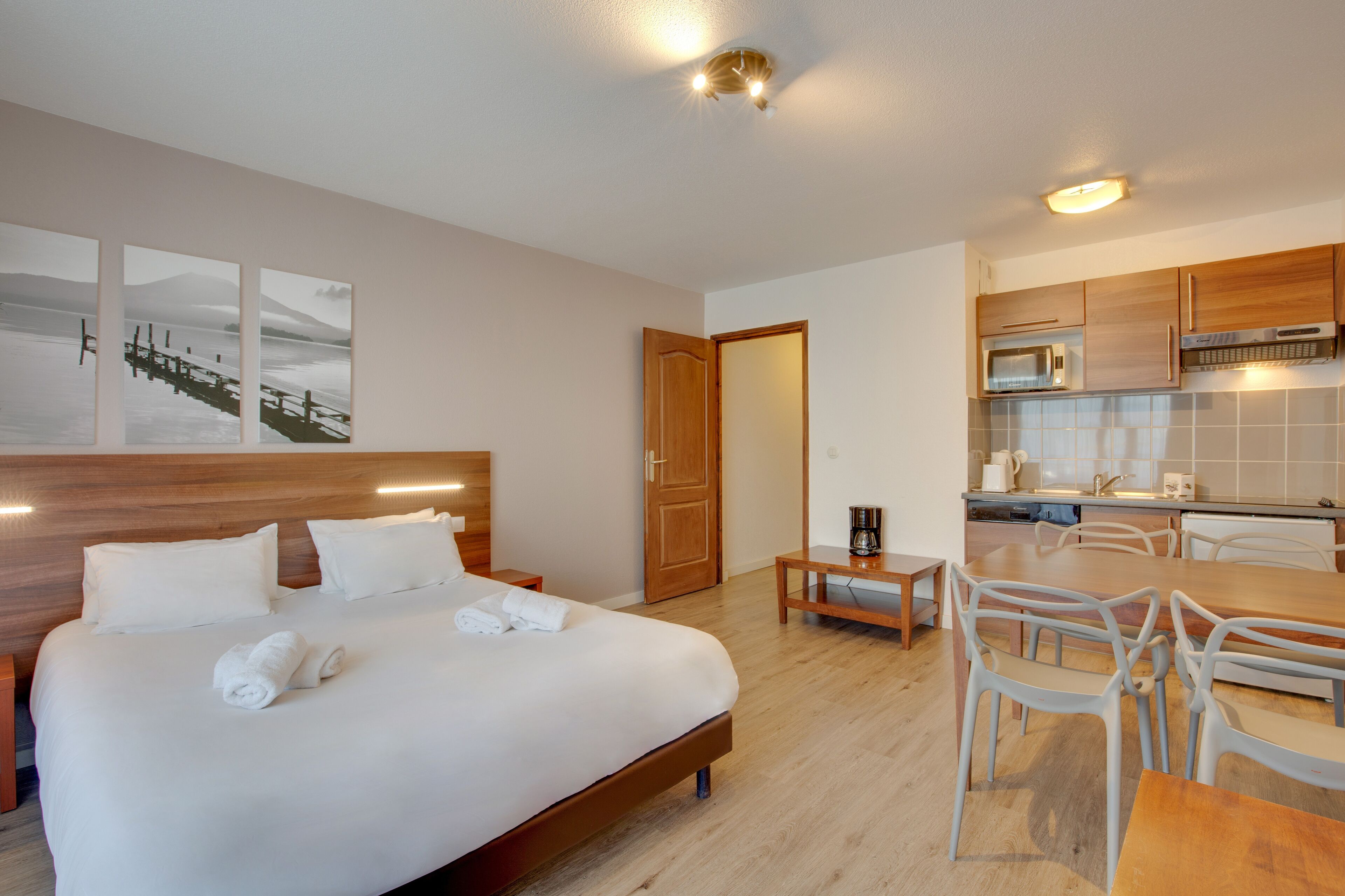 Une chambre d’hôtel avec un lit, une petite table et une kitchenette.