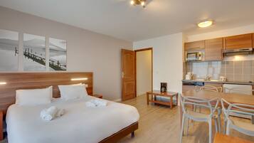 Una habitación de hotel con una cama, una mesita y una kitchenette.