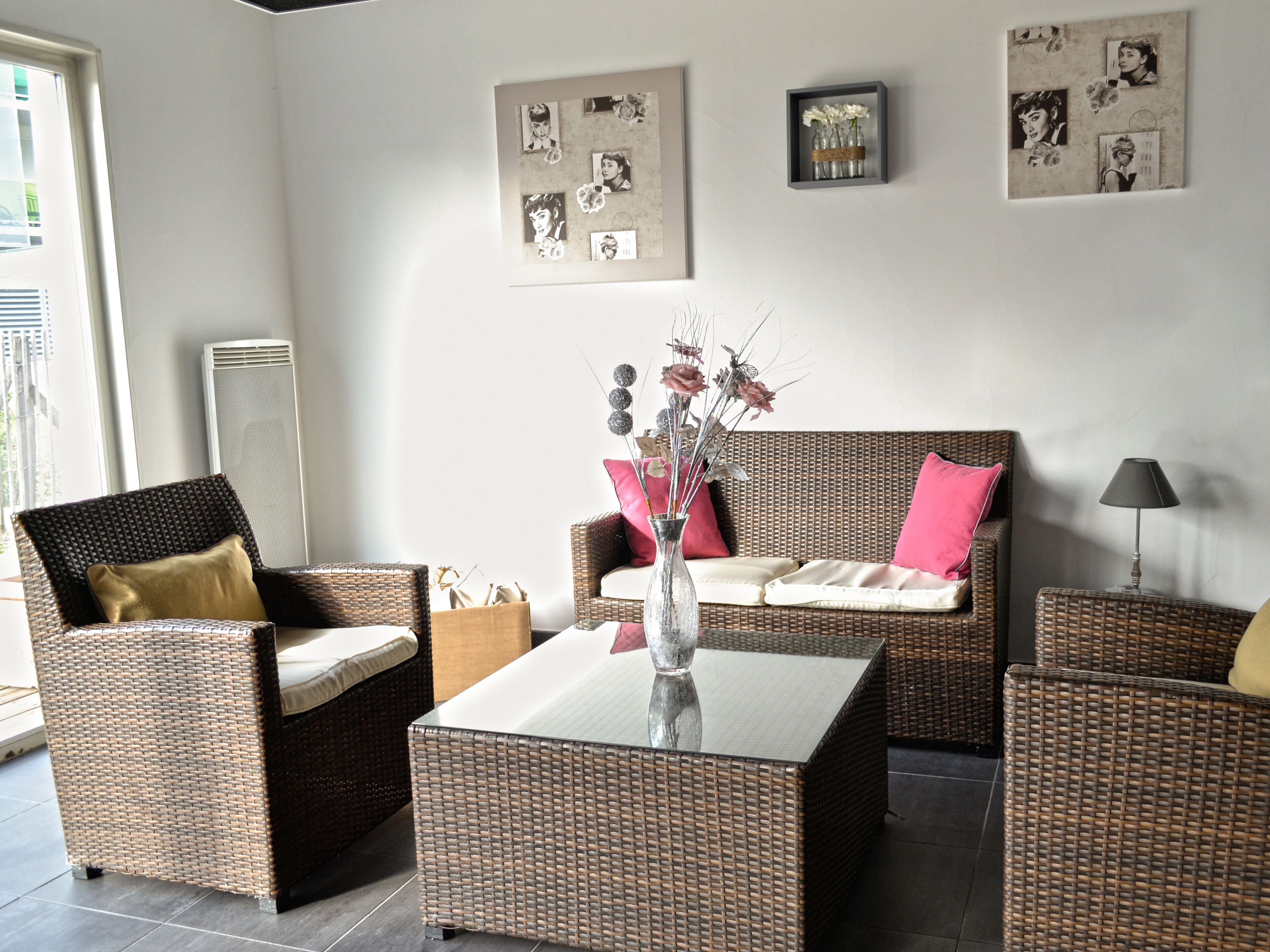 Una sala moderna con muebles de mimbre, una mesa de centro de vidrio y decoración en la pared.