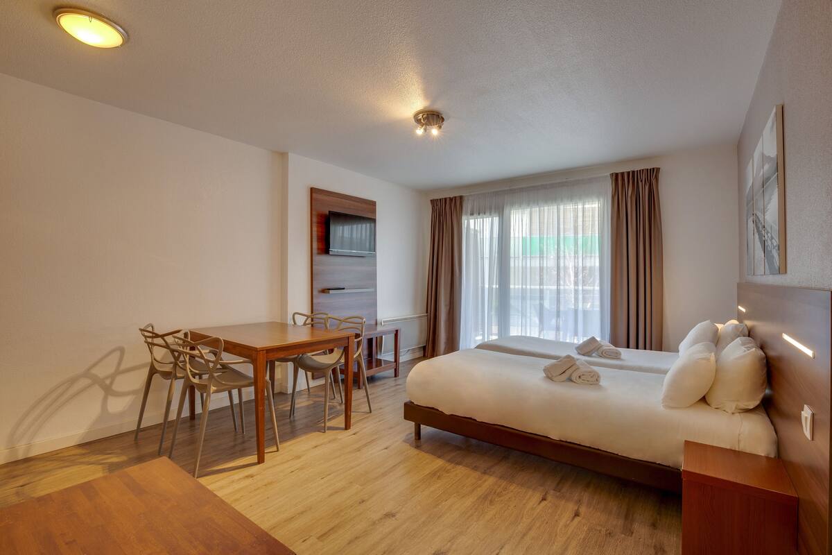 Una habitación de hotel con cama, escritorio y una silla.