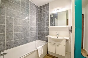 A bathroom with a bathtub, a sink, and a mirror. - ResidHotel Azuréa (Aix-les-Bains)