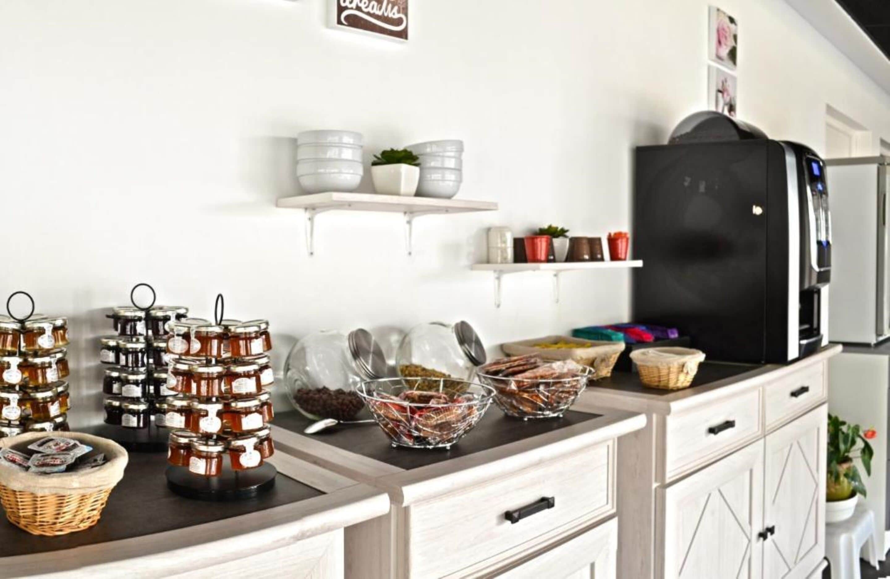 A kitchen with various food items on display, including jars of honey, bowls of fruits, and a refrigerator.