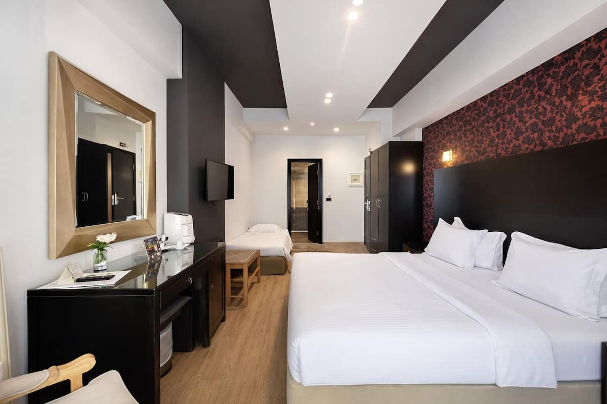 Une chambre d’hôtel moderne équipée d’un grand lit, d’un bureau avec une chaise, d’une télévision et d’un miroir.