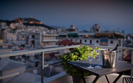 A balcony with a table, two wine glasses, and a bottle of champagne in a bucket.