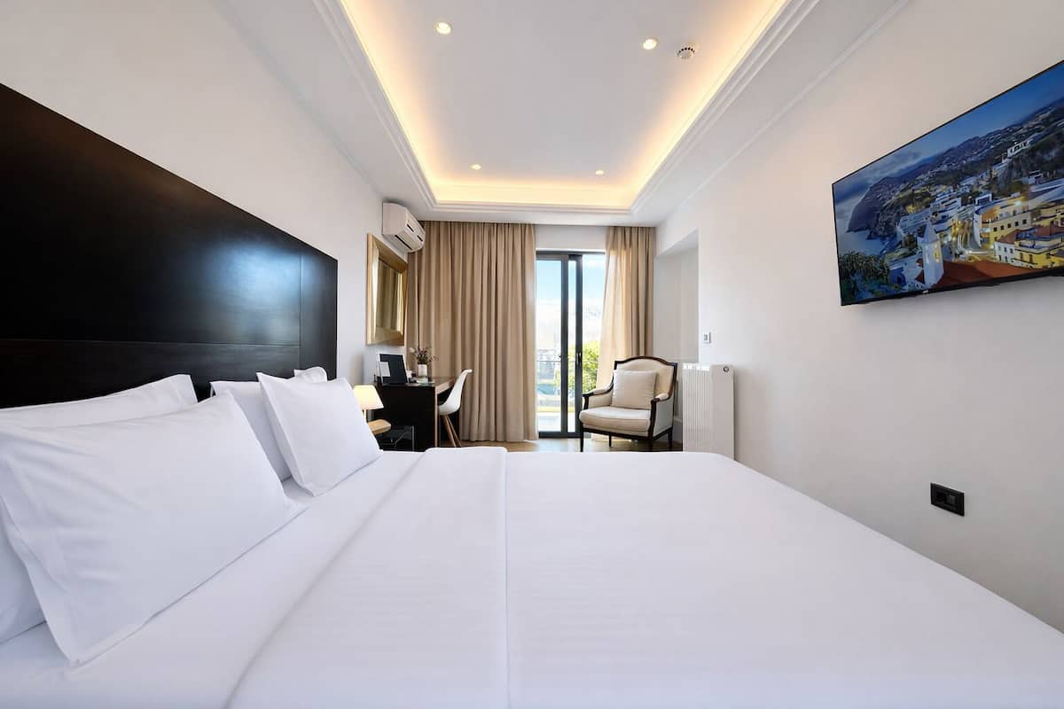 Une chambre d’hôtel avec un grand lit, un bureau, une chaise et un tableau au mur.