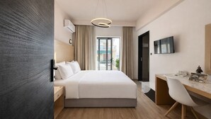 A modern hotel room with a bed, desk, and TV. - Areos Hotel (Athens)