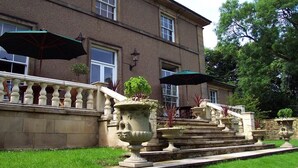 A building with a stone facade, a staircase with a balustrade, and outdoor umbrellas. - Hedgefield House Hotel (Blaydon on Tyne)