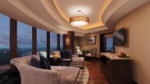A modern hotel room with a curved ceiling, a large window offering a city view, a seating area with sofas and a coffee table, a dining table with chairs, and a flat-screen TV mounted on the wall. - The Leela Ambience Gurugram Hotel & Residences - The Luxury Urban Sanctuary (Gurugram)