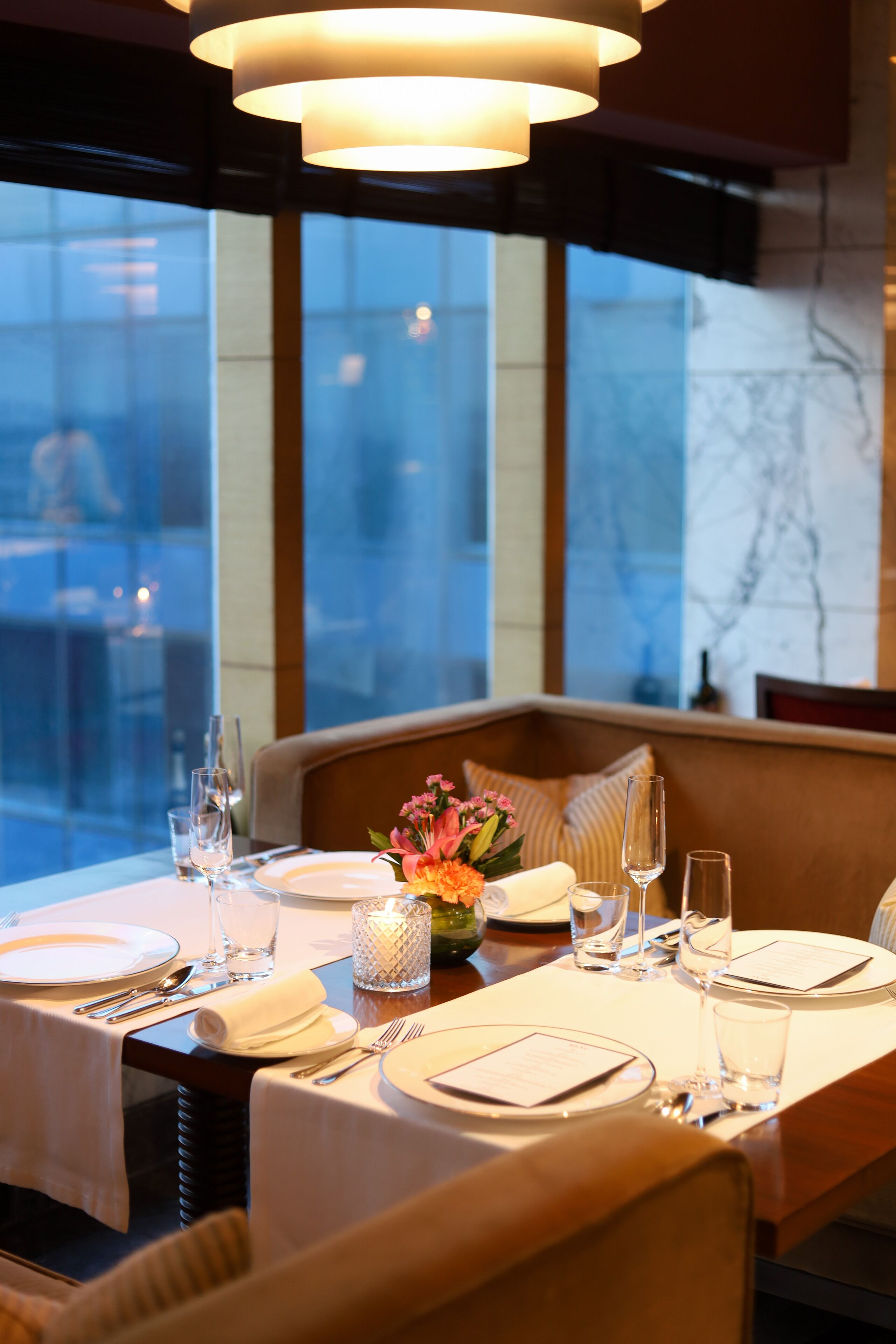 A dining table set with plates, cutlery, glasses, and a vase of flowers.