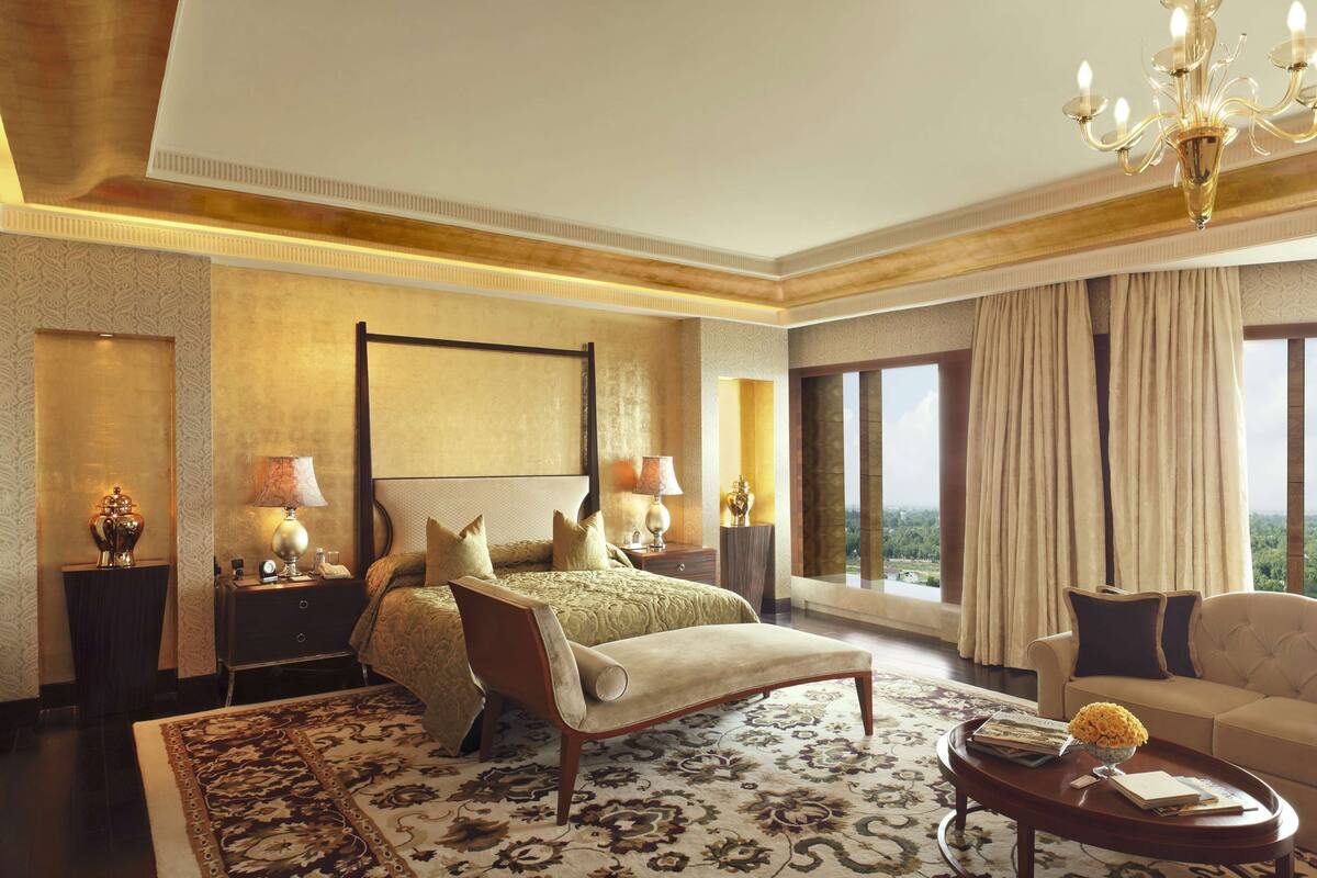 Amplia habitación de hotel con una cama grande, una zona de estar con sofá, una mesita de centro y vistas de la ciudad.