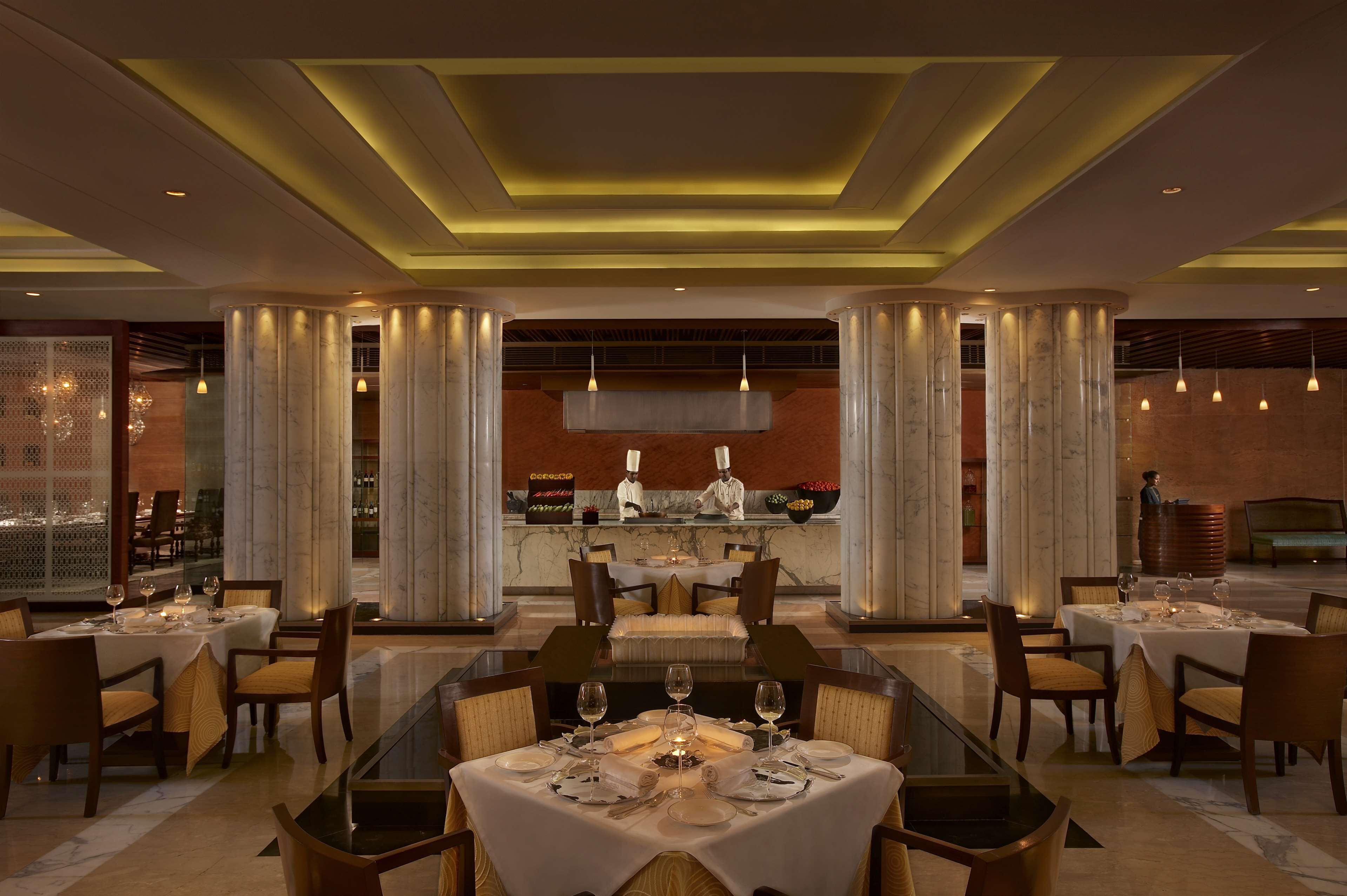 A restaurant with marble columns, a central bar, and tables set for dining.