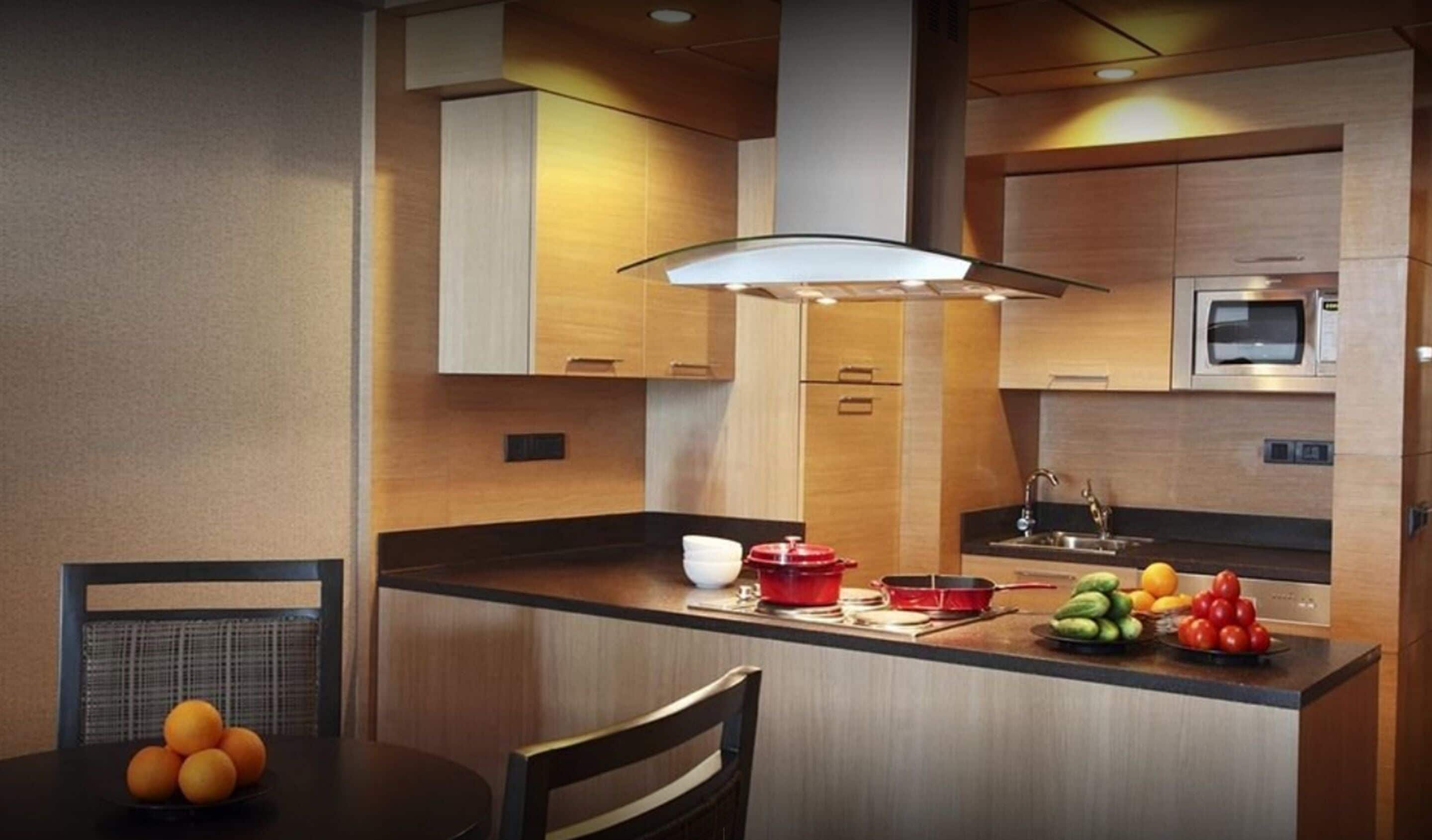 Una cocina moderna con armarios de madera, un microondas, un lavamanos y un comedor con mesa y sillas.