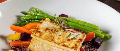 A plate of food with grilled fish, vegetables, and a side of red beans.