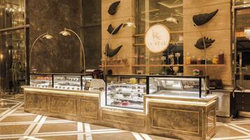 A dessert display counter with a marble floor, a glass case with various desserts, and a sign with the logo 'Le Réve'.