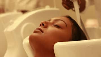 A person lying in a bathtub with a showerhead above, indicating a spa or bath facility.