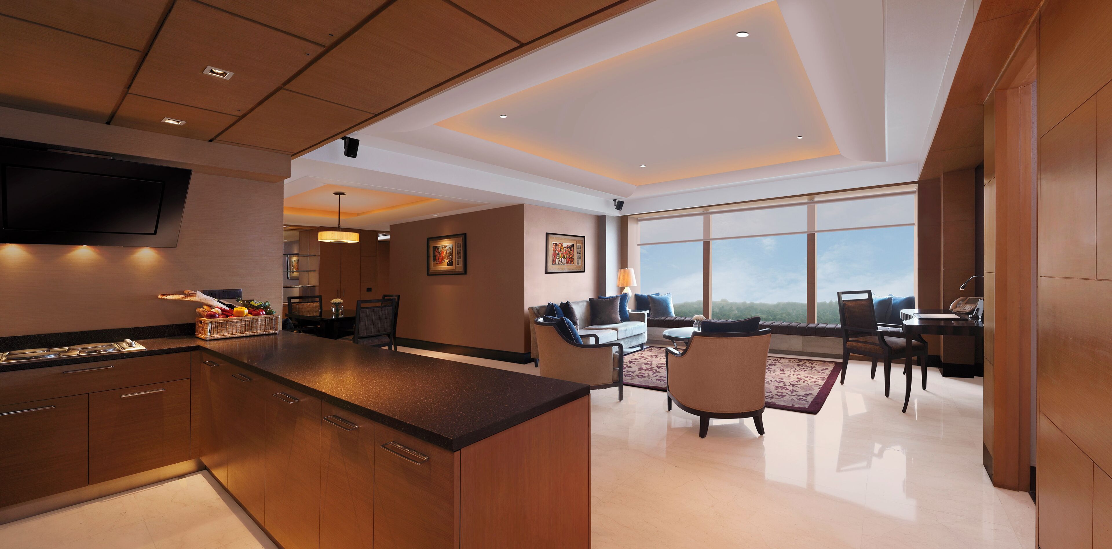A modern kitchen with a central island, dining area with chairs and a table, and large windows offering a view.