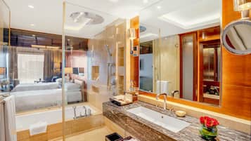 A modern bathroom with a glass-enclosed shower, a large mirror, and a marble countertop.
