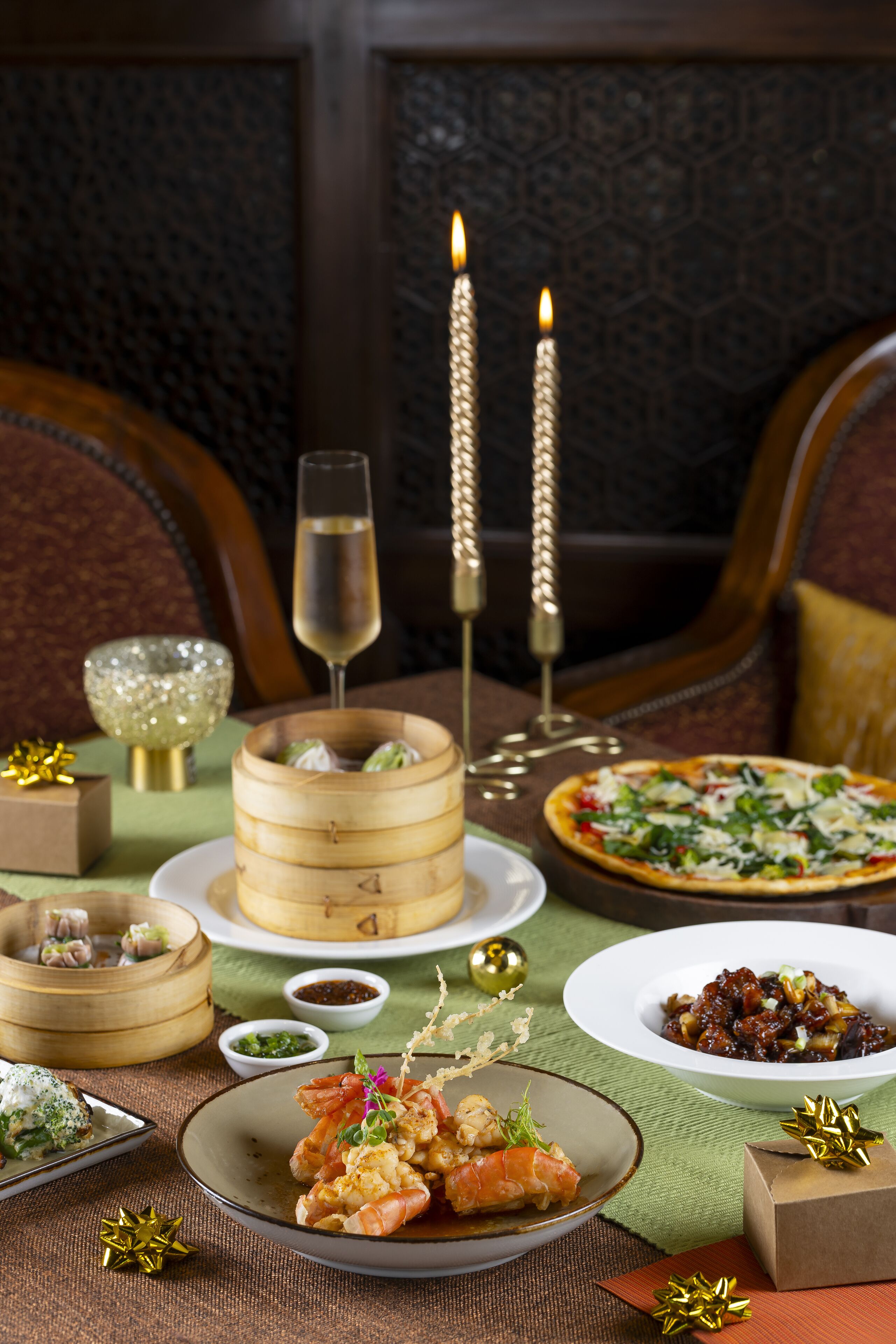 A dining table with various dishes, a glass of champagne, and candles.