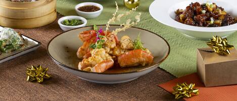 Una mesa de comedor con diversos platos, una copa de champán y velas.