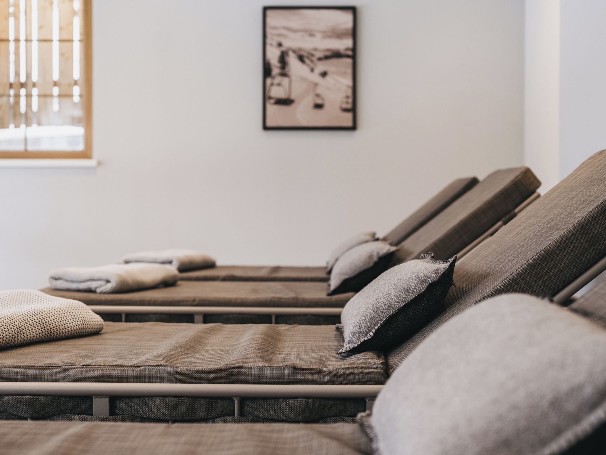 A room with a massage table, pillows, and a framed picture on the wall.