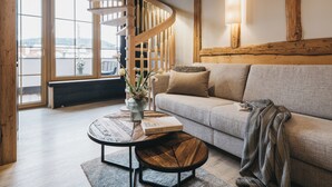 Ein modernes Wohnzimmer mit Wendeltreppe, einer Couch, einem Couchtisch und Blick durch große Fenster.