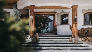Ein Gebäudeeingang mit Holzbalken, einer Steintreppe und einer Blumenvase.