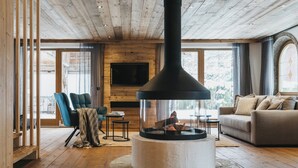Ein gemütliches Wohnzimmer mit Kamin, Holzböden, einer Couch und einem an der Wand befestigten Fernseher.