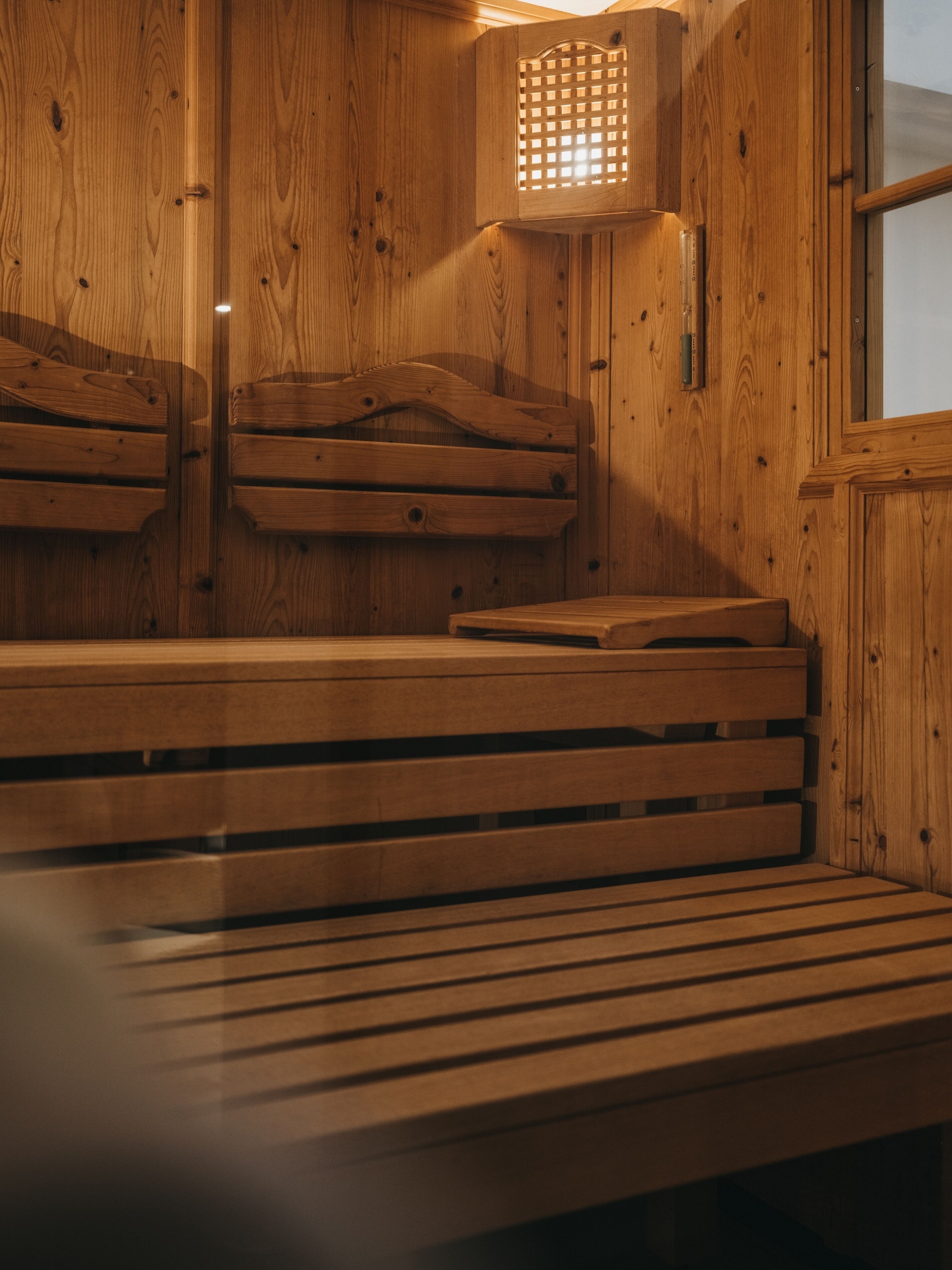 A wooden sauna with benches and a ventilation grille.