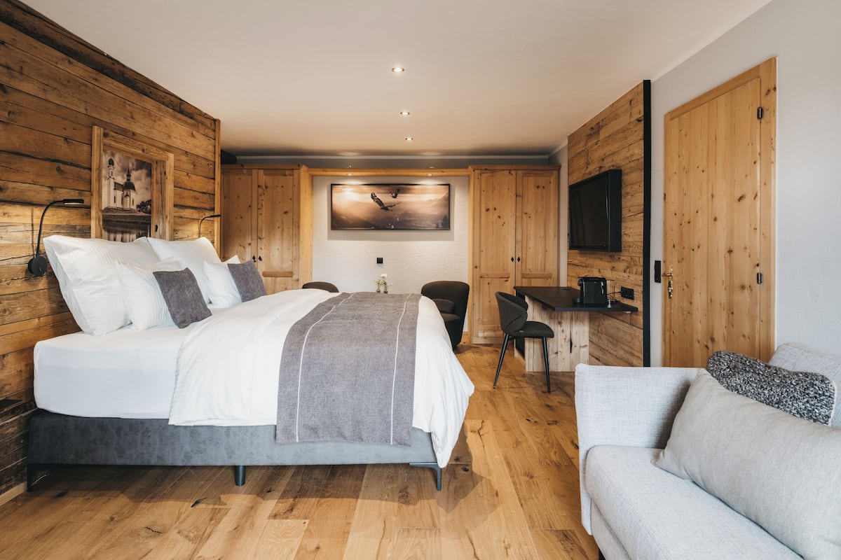 A modern bedroom with a large bed, a desk, and a sofa.