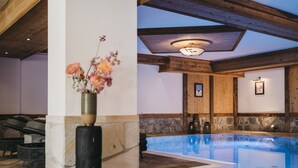 Ein Poolbereich mit Steinböden, Holzboden und einer Vase mit Blumen.