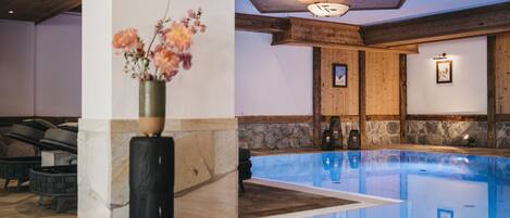 A pool area with stone flooring, a wooden ceiling, and a vase with flowers.