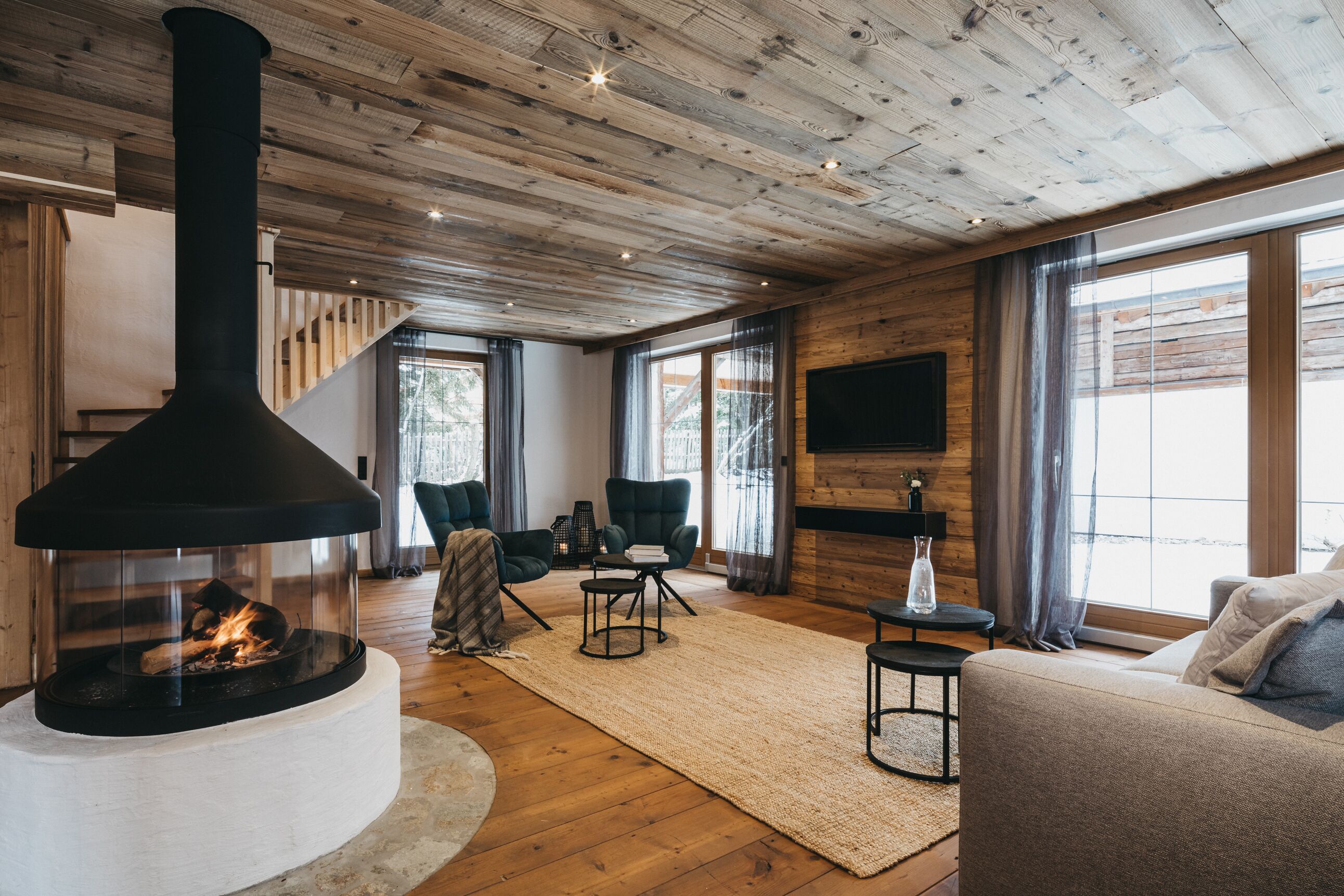 A cozy living room with a large fireplace, wooden ceiling, and comfortable seating.