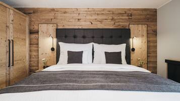Een slaapkamer met een houten hoofdbord, twee bedlampjes en een bed met wit beddengoed.