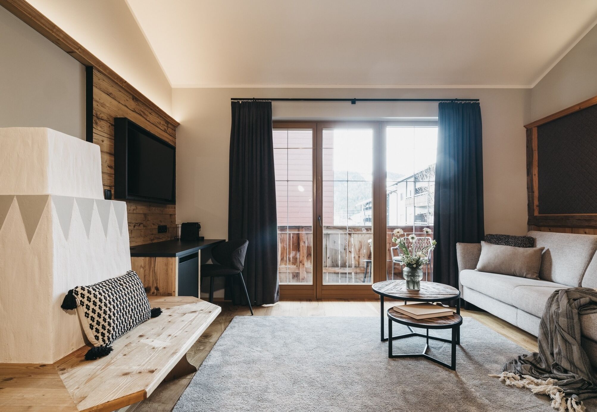 A modern living room with a sofa, a bench, a coffee table, and a TV mounted on a wooden wall.