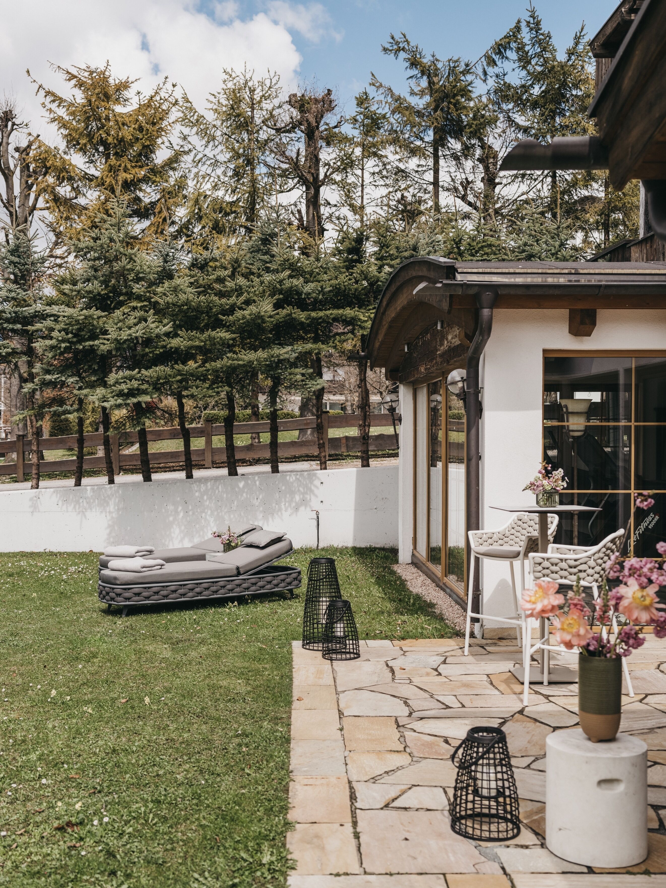 A patio with a stone floor, outdoor seating, and a view of trees.