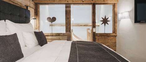 Un dormitorio con una cama grande, vigas de madera en el techo y vistas al exterior, además de una decoración con estrellas en la pared.
