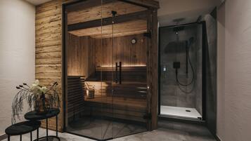 Een moderne badkamer met een houten sauna, een glazen douchecabine en een klein tafeltje met een bloevas.