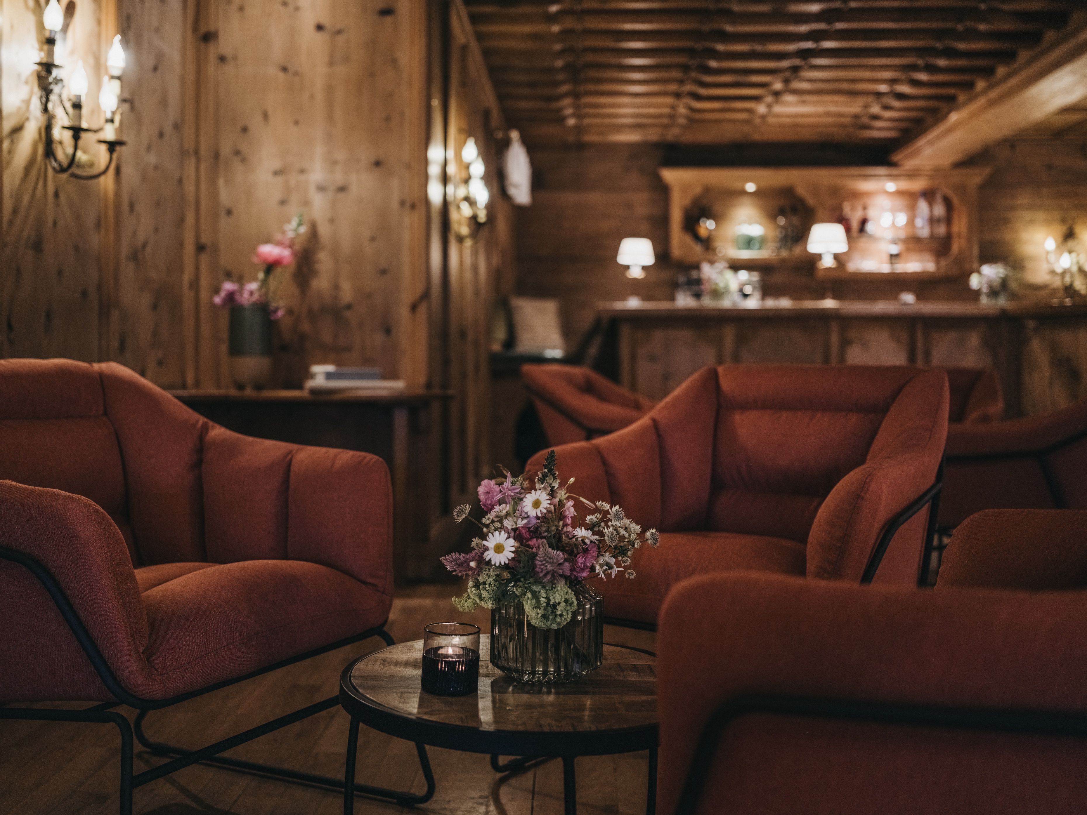 Een gezellig interieur met houten wanden, een bar en zitplaatsen, met een vaas bloemen op een tafel.