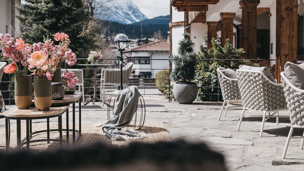 Eine Terrasse im Freien mit Steinböden, Holzmöbeln und Pflanzen in Töpfen.