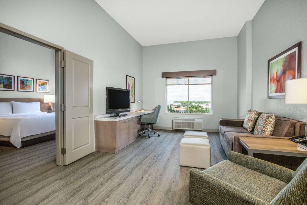 A hotel room with a bed, desk, computer, and seating area.