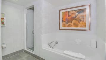Een moderne badkamer met een glazen douchecabine, een bad met een handdoek en een lijstwerk kunstwerk aan de muur.