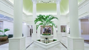 A spacious lobby with a central fountain, white columns, and a high ceiling.