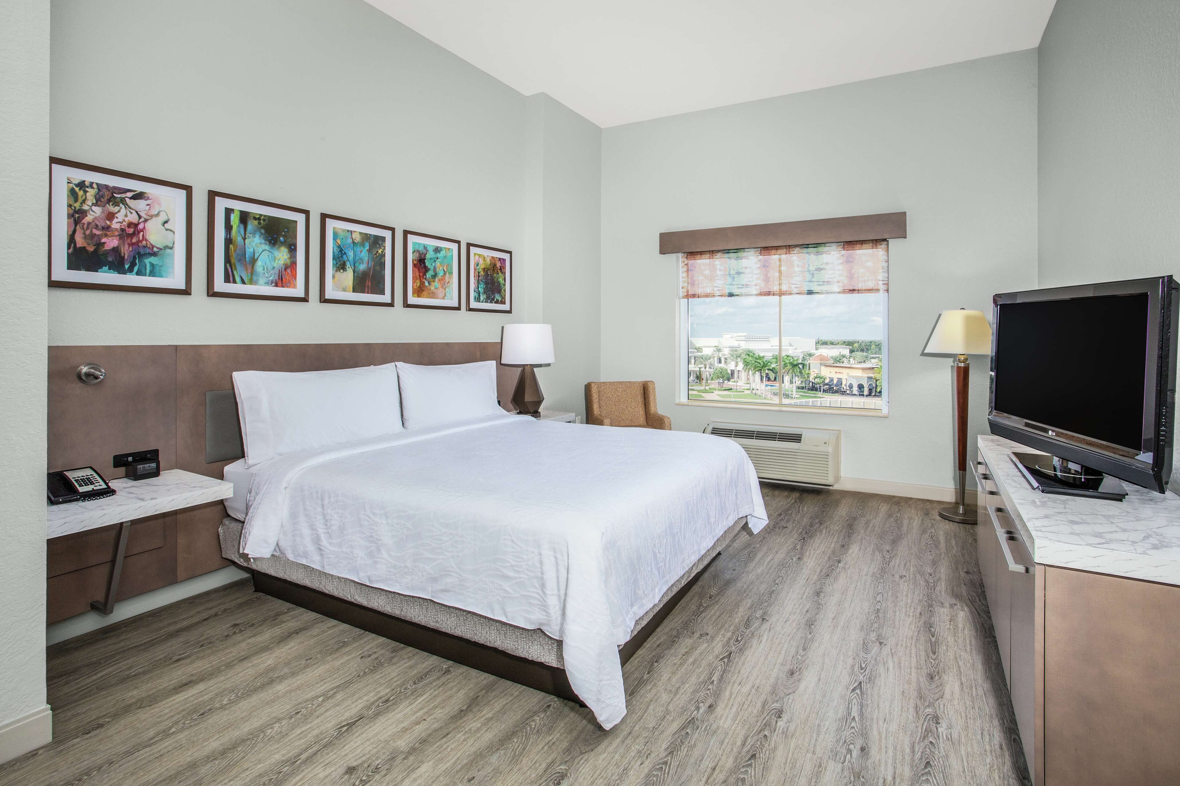 Habitación de hotel con cama, escritorio, televisor y ventana con vistas.