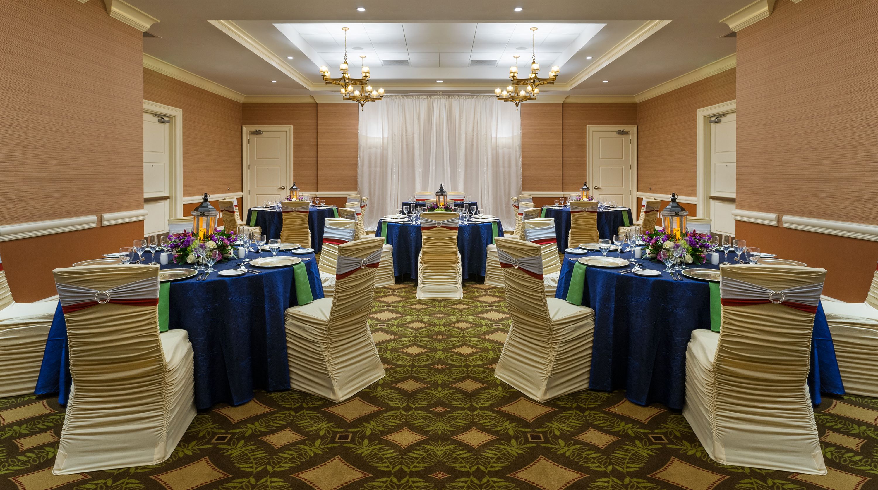 Une salle de banquet avec des tables rondes, des chaises et un lustre.